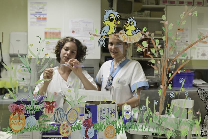 Infirmières derrière une vitre avec dessins enfantins